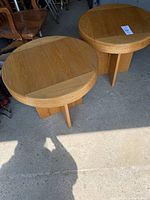 Two solid wood round side tables shown from above and front angle, showing tops and base structure