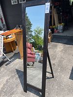 Front view of the full-length mirror showing dark wood frame and standing support