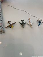 Four miniature plane models positioned next to a ruler for scale.