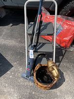 Full lot showing Bissell Magic Vac, Turbo Tiger handheld vacuum, wicker basket with cords/accessories, and 3-step stool ladder outdoors on asphalt.
