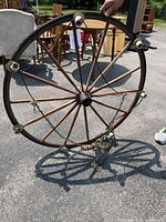 Full view of round wooden wagon wheel chandelier showing 7 light sockets around the rim, held by a person outdoors on pavement.