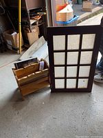 Wooden magazine rack beside a wooden window frame with 12 textured glass panes.