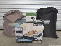 Photo shows three packed airbeds: one Intex in box, two Coleman in black and gray carrying bags, and a boxed electric air pump.