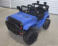 Front-side view of the blue electric ride-on toy car showing detailed front grille, tires, and seat area.