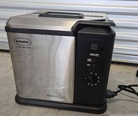 Front and side view of Butterball Professional Series electric turkey fryer showing brushed stainless steel body with black control panel and lid handle.