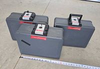 Three gray First Alert fireproof lock boxes arranged showing their front and top sides with handles and lock panels. A tape measure in front indicates about 16 inches width each.