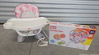 SpaceSaver high chair assembled with removable tray and pink floral cushion next to Bright Starts Flamingo Vibes baby bouncer box.