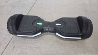 Front view of black Jetson Rave hoverboard showing footpads, LED lights, and tire design on concrete floor.