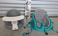 Photo showing Little Tikes gray baby booster seat with white tray and teal floor seat with striped cushion and safety straps.