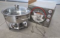 Complete NSF stainless steel chafing dish set with glass lid, metal stand, and original box.