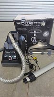 Rowenta Compact Valet garment steamer unit, flexible hose, hanger attachment, and original box visible in the background.