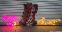 Front view of all three signs together lit up: neon pink 'You Glow Girl', bear decor with 'The Bear Den' sign, and neon yellow 'Cheers'.