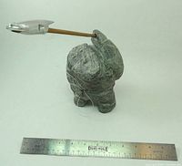 Front view showing soapstone figure with attached harpoon and ruler for scale