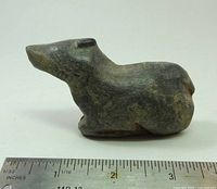 Side profile of stone caribou figurine with ruler for scale
