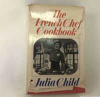 Front dust jacket of The French Chef Cookbook showing title and Julia Child photo, visible tear at top