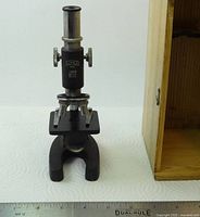 Full view of microscope next to open storage box, ruler for scale