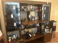 Front view of large wood display cabinet with glass doors, shelving, and various displayed items inside (not included).