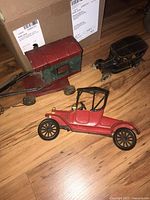 Three vintage decorative metal car figurines on wood floor, showing size and condition.