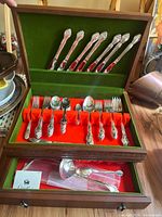 Full view of Oneida Affection stainless steel flatware set in wooden case with green and red felt lining.