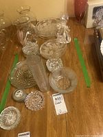 Overview of the glass collection showing plates, bowls, candy dish, and some vases and pitchers on wooden surface