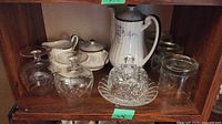 Shelf display with Paragon coffee pot, sugar bowl, creamer, glass butter dish, stemmed glasses, and clear drinking glasses