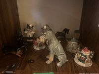 Shelf with multiple small ceramic or porcelain figurines including Goebel dog and horse figurines, some with damage.