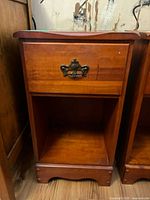 Front view of wood nightstand showing drawer with metal handle and open bottom shelf.