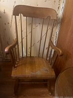 Front view of wooden rocking chair showing scratches on seat and missing back bar