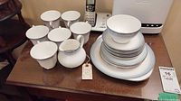 Photo showing six teacups, sugar bowl, creamer, stacked serving plate, and six side plates arranged on table