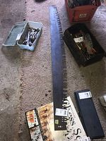 Full length view of the 60 inch saw blade laid on carpet showing its length and general condition including other tools not included in sale.
