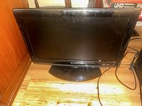Front view of Sharp 19-inch flat screen television showing the screen, bezel, and stand base on wooden floor.