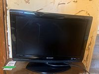 Front view of Sharp 19 inch TV on stand, showing the screen and logo.