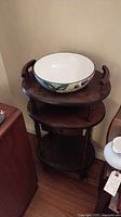 Wooden stand with ceramic bowl on top, showing the shape and condition of the stand and drawer.