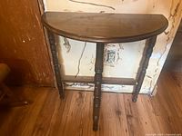 Front view of semi-circular wood side table showing the turned legs and polished surface.