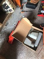 Box containing three used plastic spray bottles of various sizes with trigger nozzles and orange road reflector flares partially visible underneath.