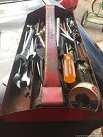 Overview photo showing multiple tools including screwdrivers, pliers, sockets, and a metal tray with red handle.