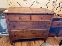 Front view of vintage wood dresser showing four drawers, wood grain, and burn marks on the edge of the top surface.
