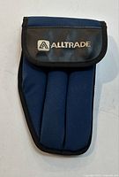 Front view of blue and black Alltrade tool pouch with flap showing brand logo.