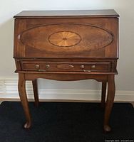 Front view of cherry stained Ashley drop front secretary desk showing carved oval medallion detail and brass hardware.
