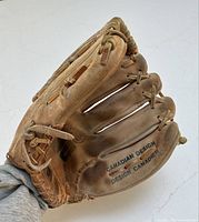 Top side view of the worn DR100 baseball glove showing leather texture and lacing details.