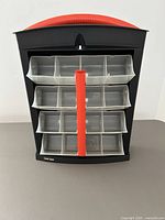 Front view of Black & Decker modular storage system showing 16 clear bins with red handle and black frame.