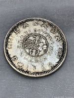 Obverse of the 1964 Canadian silver dollar showing the commemorative floral design with Charlottetown and Quebec City inscriptions, date 1964, and circulated condition.