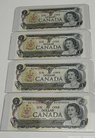 Front sides of four Canadian 1973 one dollar bills with Queen Elizabeth II portrait and Canadian coat of arms, all stored in protective sleeves.