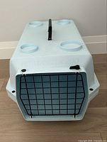 Front view of light blue Pet Voyageur 200 cat carrier with black metal wire door and locking knobs.