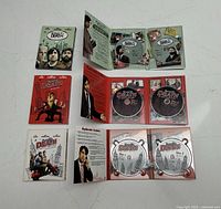 Three open DVD and Blu-ray sets of Bored To Death showing cases, booklets, and discs for Seasons 1-3.