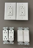 Front view of the 2 GFCI receptacles with faceplates, 2 standard receptacles and 2 rocker switches without faceplates, all white Decora style.