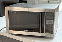 Front view of the stainless steel microwave showing the black glass door with Euro Touch and Sanyo logos, and the digital control panel with buttons and display.