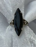 Top view of the sterling silver ring with marquise-shaped black stone on white fabric backdrop.