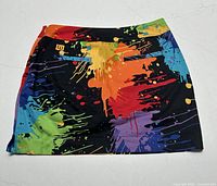 Front side of black Women’s Loudmouth paintball skort with bright multi-color paint splatter pattern.