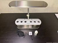 Front view of AeroGarden unit with power adapter and nutrient bottle